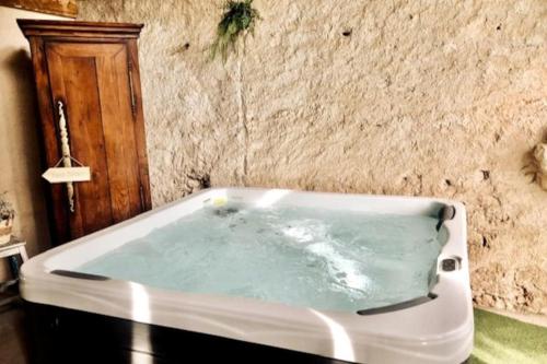 a bath tub in a bathroom with a stone wall at Le Mas Réolais in Saint-Sève