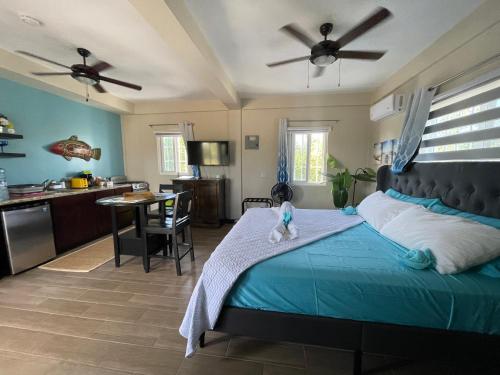a bedroom with a blue bed and a kitchen at Costa Nube in Caye Caulker