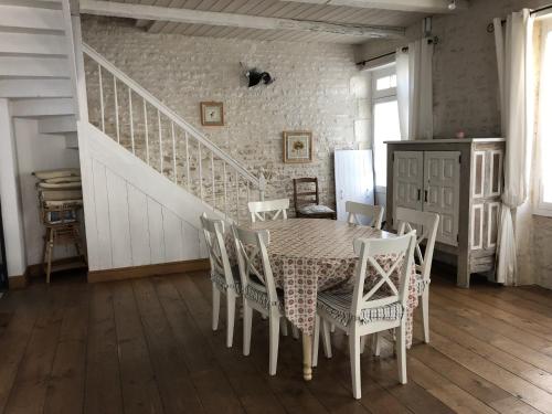 une salle à manger avec une table et des chaises et un escalier dans l'établissement Maison de ville confortable 200m de la mer, au Château-dʼOléron
