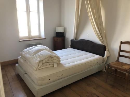 a bed in a room with a window and a chair at Maison de ville confortable 200m de la mer in Le Château-dʼOléron