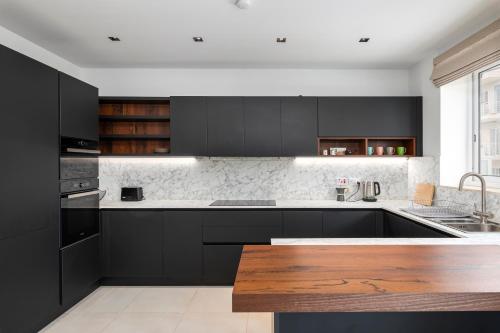 a kitchen with black cabinets and a wooden table at Modern 3BR Stylish Apartment with large Balcony - Close to St Julians and St Georges Bay in Is-Swieqi