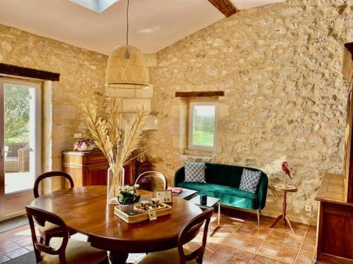 a living room with a table and a green couch at Le Mas Réolais in Saint-Sève
