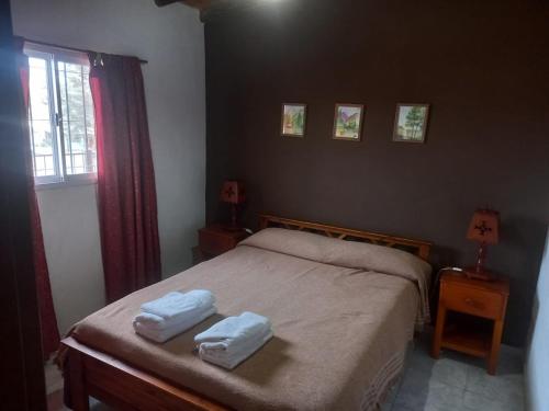 a bedroom with a bed with two towels on it at Cabañas DAYMA in Trapiche