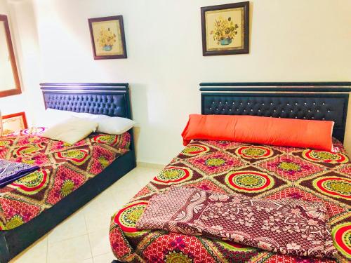 - une chambre avec 2 lits et des couvertures colorées dans l'établissement شاليه جديد عائلي كبير, à Dawwār al Ḩajj Aḩmad