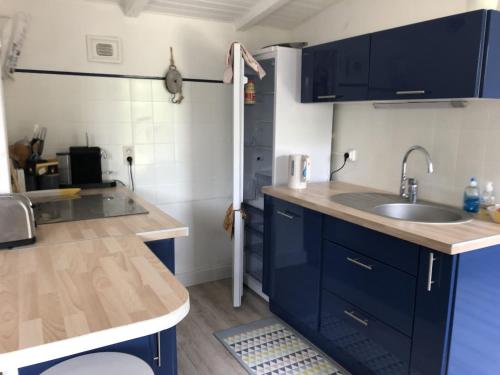 a kitchen with blue cabinets and a sink at La Cabane de peche de la Cotiniere in Saint-Pierre-dʼOléron
