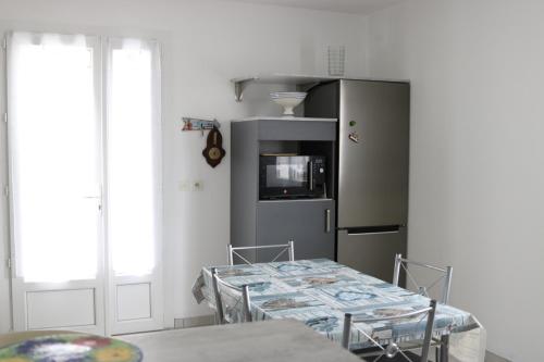 une cuisine avec une table et un réfrigérateur dans l'établissement La petite maison a Mamy La Cotiniere, à Saint-Pierre-dʼOléron