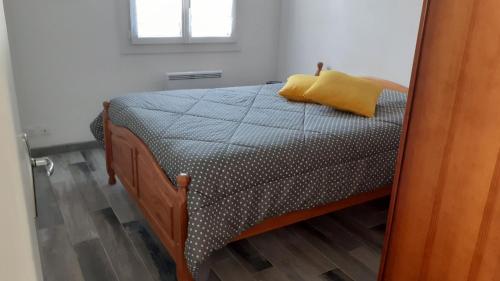 - une chambre avec un lit doté d'un oreiller jaune dans l'établissement La petite maison a Mamy La Cotiniere, à Saint-Pierre-dʼOléron