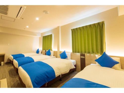 een rij bedden in een kamer met groene gordijnen bij HOTEL LANTANA Naha Kokusai Street - Vacation STAY 65213v in Naha