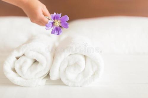 a hand holding a purple flower above three towels at Melati Park in Sungai Petani