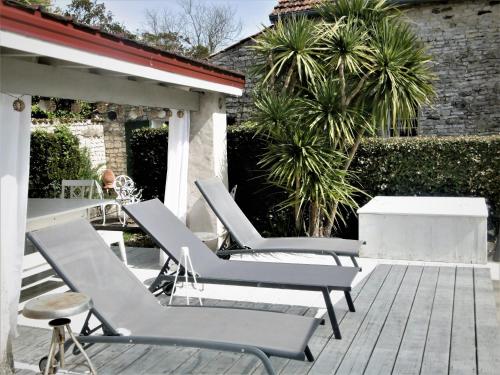 a group of lounge chairs sitting on a patio at Le Chai Maison de charme pour tribu joyeuse in Grand-Village-Plage