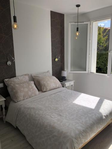 une chambre avec un grand lit et deux fenêtres dans l'établissement Le nid douillet du Chateau, au Château-dʼOléron