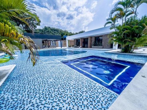 een zwembad met een blauwe tegelvloer en een huis bij Casa Quinta de Lujo Villeta MyS in Villeta