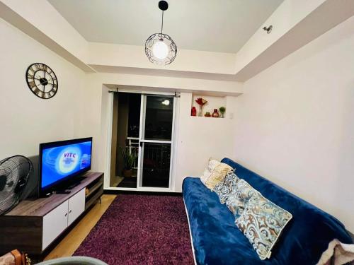 a living room with a blue couch and a tv at 1 BR Condo Unit at The Celandine Condominium near Ayala Cloverleaf Mall in Manila