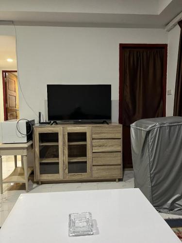 a living room with a television on a wooden entertainment center at Mall Suites Hotel in Bangkok