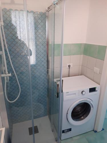 y baño con ducha y lavadora. en Villa la Torre Levante, en Torre dei Corsari