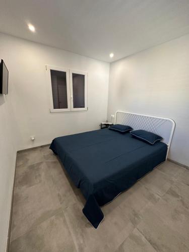 a bedroom with a bed with a blue comforter and two windows at Casa de alquiler Moncófar Playa in Moncófar