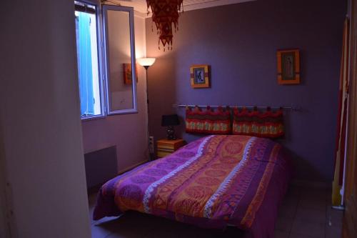 een slaapkamer met een bed met paarse muren en een raam bij Petite maison bord et vue mer, 55 m2 in Martigues