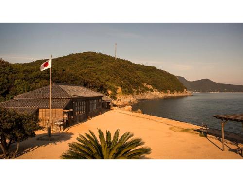Ikeda的住宿－Kokuminshukusha Shodoshima - Vacation STAY 59346v，水体旁建筑物上的旗帜