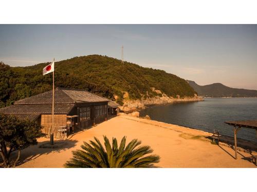 Ikeda的住宿－Kokuminshukusha Shodoshima - Vacation STAY 59365v，水体旁建筑物上的旗帜