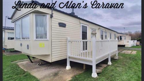 a small white trailer with a porch and a house at Linda/Alan's Happy Holiday Home in Rhyl