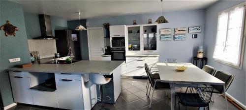 une cuisine avec un comptoir et une table avec des chaises dans l'établissement Villa Ohana proche centre-ville, au Château-dʼOléron