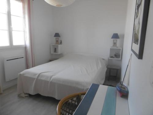 une chambre blanche avec un lit et une table dans l'établissement L Azuree en front de mer, à Le Port-des-Barques