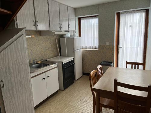 une cuisine avec un évier et une table avec des chaises dans l'établissement Altitude Location Montagne, à La Bourboule