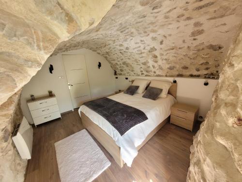 ein Schlafzimmer mit einem Bett und einer Steinmauer in der Unterkunft Chaleureuse bergerie rénovée. in Tourrette-Levens