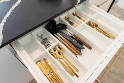 a white drawer with gold utensils in it at Srebrna Luxury Apartments - willa fabrykancka - wnętrza premium in Łódź