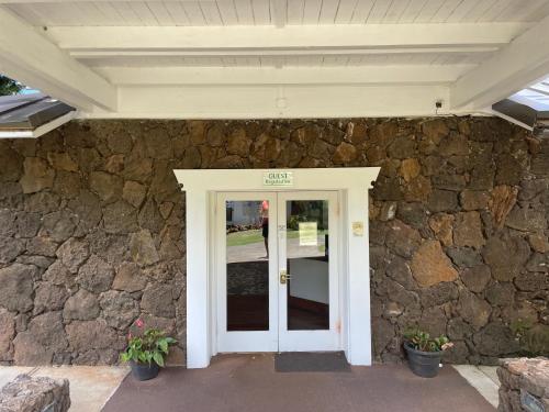 a stone house with a white door and a stone wall at Step to beach New Quiet Kiahuna Plantation Remodeled 2 bedroom condo with AC in Koloa