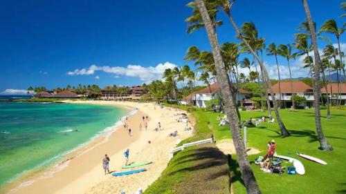 a group of people on a beach near the ocean at Step to beach New Quiet Kiahuna Plantation Remodeled 2 bedroom condo with AC in Koloa