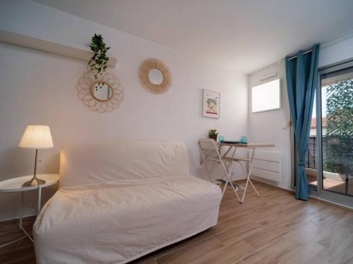 a white bedroom with a bed and a table and a window at Appartement tout équipé terrasse parking privatif in Six-Fours-les-Plages