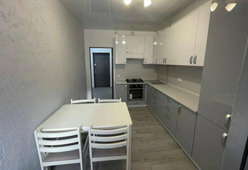 a kitchen with a white table and white chairs at Apartment COMFORT on Ruska street in Chernivtsi