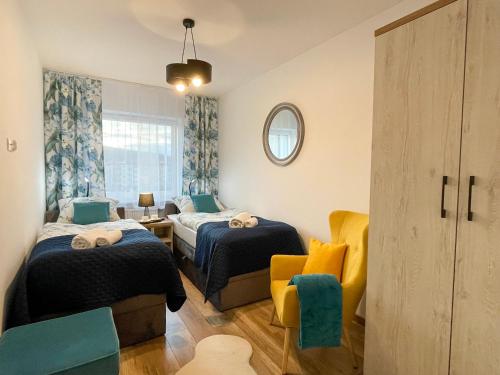 a small room with two beds and a chair at Apartament Błękitne Spa in Ustrzyki Dolne