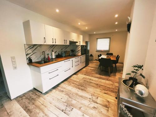 a kitchen with white cabinets and a dining table at Casa Di Monaco in Glees