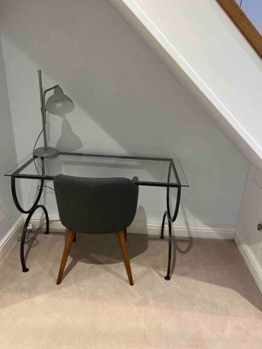 a glass desk with a chair and a lamp at The Chapel, Cotswolds in North Cerney