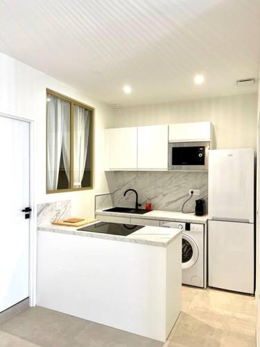 La cuisine blanche est équipée d'un évier et d'un réfrigérateur. dans l'établissement Appartement moderne + Parking à 50m de la mer, à La Ciotat