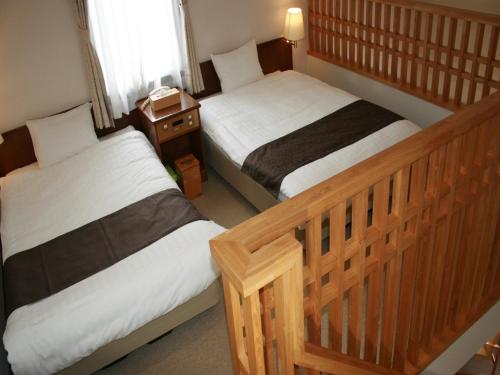 een slaapkamer met 2 bedden en een nachtkastje bij Japanese Auberge Plaza Ryokufu Natural Hot Spring - Vacation STAY 03215v in Shimo-orube