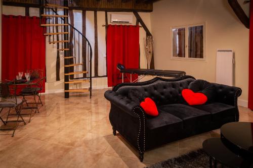 ein Wohnzimmer mit einem schwarzen Sofa und roten Kissen in der Unterkunft Pour Toi et Moi - Loveroom in Saint-Martin-des-Bois