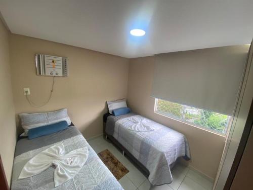 a small room with two beds and a window at Apartamento Ideal Flores in Manaus
