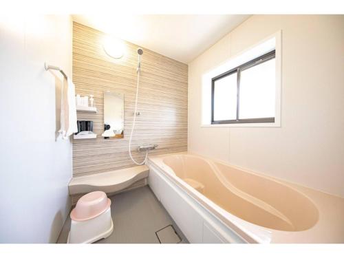a bathroom with a tub and a toilet and a window at Dan Hiyori - Vacation STAY 08978v in Ebino