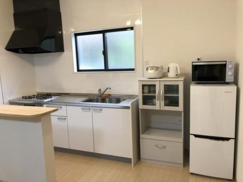cocina con armarios blancos, fregadero y microondas en Sunset Village - Vacation STAY 15292v en Onomichi