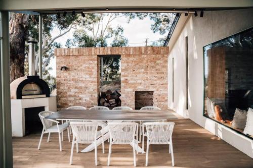 a patio with a table and chairs and a fireplace at Suyapto House in Hahndorf