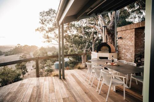 a wooden deck with a table and chairs and a fireplace at Suyapto House in Hahndorf