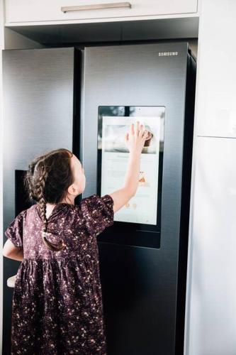 a woman looking at a picture on the side of a refrigerator at Suyapto House in Hahndorf