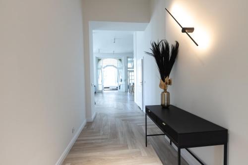 a hallway with a black table and a white wall at Srebrna Luxury Apartments - willa fabrykancka - wnętrza premium in Łódź