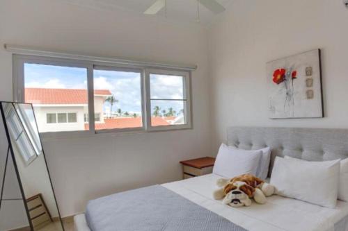 un osito de peluche sentado en una cama en un dormitorio en BAVARO PUNTA CANA Apartamento con Piscina, en Punta Cana