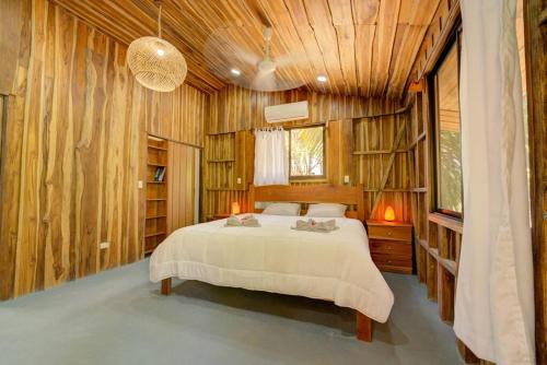 1 dormitorio con 1 cama en una habitación con paredes de madera en Sámara Tarantela Houses, Casa Bambú, en Sámara