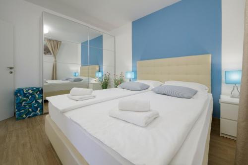 a white bedroom with a large white bed and a mirror at Serviced Family Suite by the sea, Mezaninе lеvеl in Bol