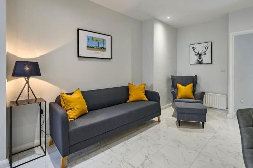a living room with a blue couch and yellow pillows at Belfast Luxury Lets - Windsor Townhouse in Belfast